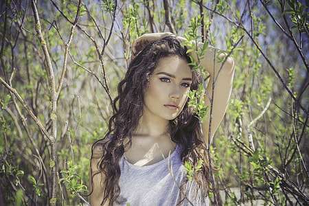 selective focus photography of a woman in gray heather tank top surrounded by brown twigs thumbnail