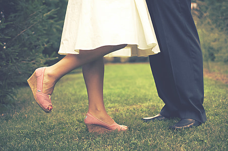 woman wearing pink-and-brown peep-toe wedge shoes and man wearing black leather dress shoes thumbnail