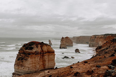 brown rocky hills beside body of water under cloudy sky thumbnail