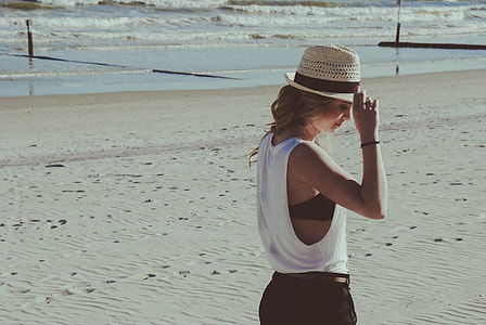 woman wearing white sleeveless shirt on white sand near body of water during daytime thumbnail