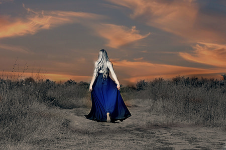 woman with blue sleeveless flare maxi dress walking on road during golden hour thumbnail