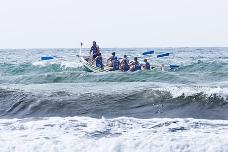 group of men on boat with oars paddling hard violent waves during daytime thumbnail