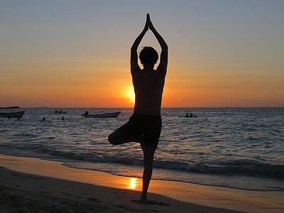 silhouette of person standing on beach doing yoga pose thumbnail