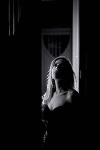 grayscale photo of woman standing on doo r thumbnail