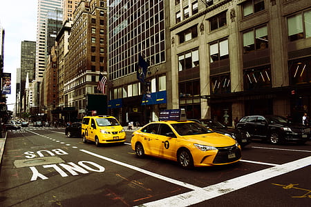 yellow sedan in middle of street during daytime thumbnail