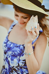 woman in blue floral dress holding shell thumbnail