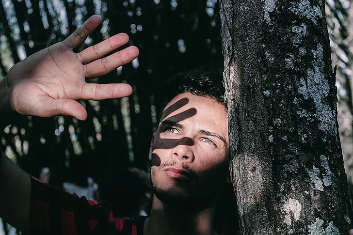 man standing near tree illuminated by sunlight during daytime