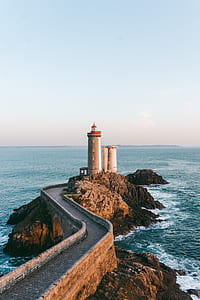 brown and red lighthouse near body of water at daytime thumbnail