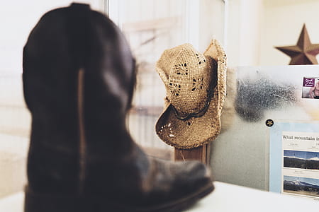 selective focus photography of brown cowboy hat hanged beside wall thumbnail