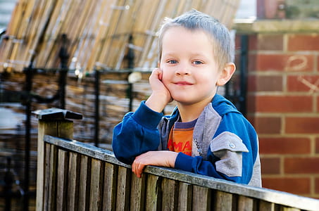 boy gray and blue zip-up jacket leaning on gray wooden terrance thumbnail
