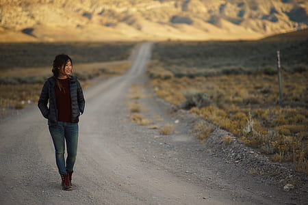 woman walking alone the road near grasses thumbnail