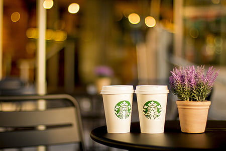 two white Starbucks disposable cups on black wooden table thumbnail