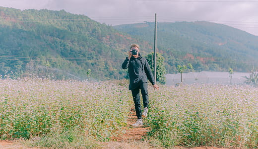 Person Holding Camera Surrounded by Plants thumbnail