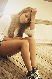 woman in white scoop-neck long-sleeved shirt sitting on brown wooden floor thumbnail