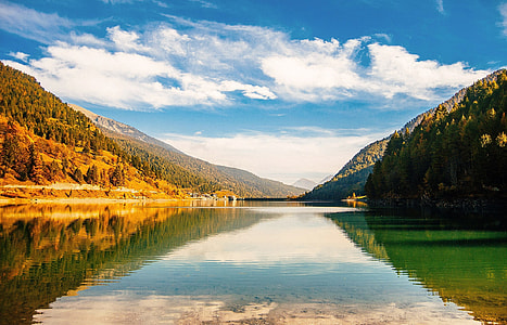 body of water beside mountain with trees during daytime thumbnail