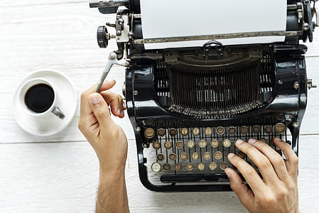 person using typewriter with coffee on the side thumbnail