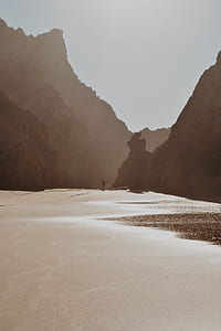 person standing on body of water surrounded mountains thumbnail