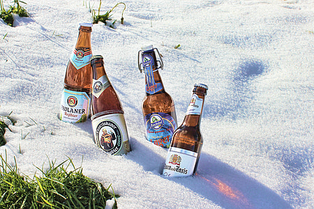 four brown glass bottles on white sand at daytime thumbnail