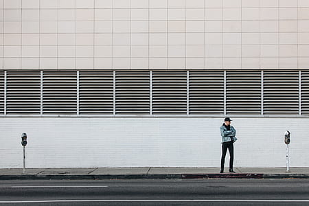 man standing on street beside concrete wall thumbnail