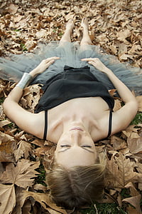 woman wearing black camisole and gray tutu skirt lying on brown leaves thumbnail