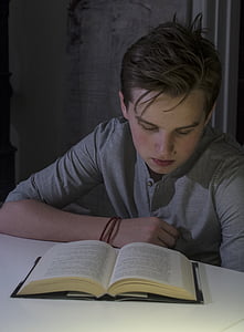 boy wearing gray henley shirt reading book thumbnail