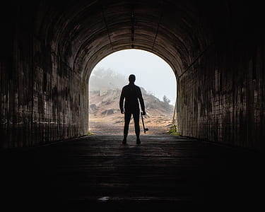 silhouette of person standing on arc bridge during daytime thumbnail