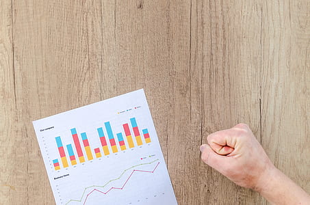 white and multicolored graph on brown surface near right human fist thumbnail