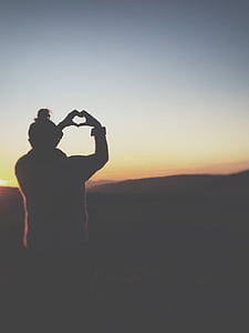 silhouette of a person doing heart hand gesture thumbnail