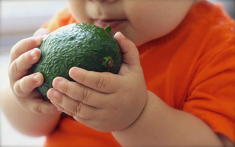 baby holding green fruit thumbnail