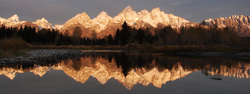 mountains surrounded with trees near body of water thumbnail