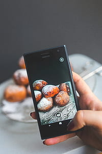 Woman hand taking picture of doughnuts thumbnail