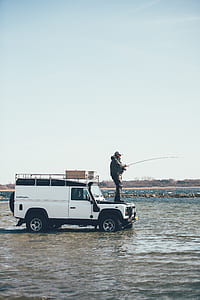 person fishing on top of white Land Rover SUV thumbnail