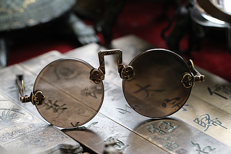 selective focus photo of round brown lens sunglasses with gold frames on kanji tiles thumbnail