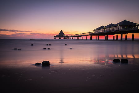 silhouette photography of cottages on a bridge above sea thumbnail