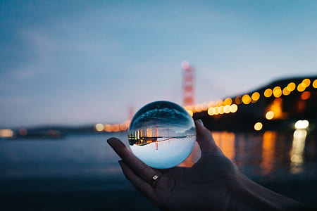 person holding glass ball reflecting bridge thumbnail