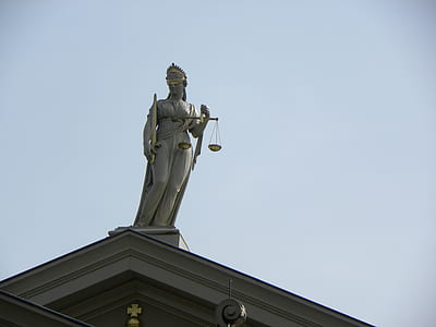 Lady Justice statue on top of building under clear sky thumbnail
