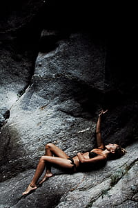 woman wearing bikini laying on grey rock thumbnail