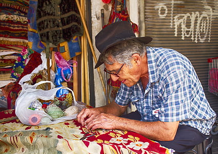 man making carpet while sitting on chair thumbnail