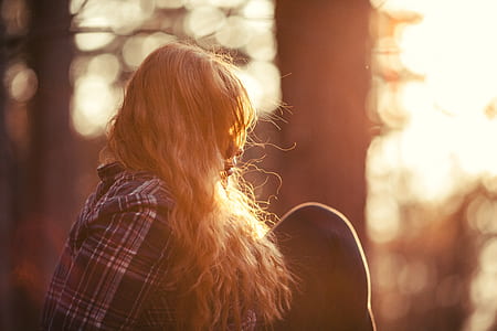 woman sitting near trees shallow focus photography during sunset thumbnail