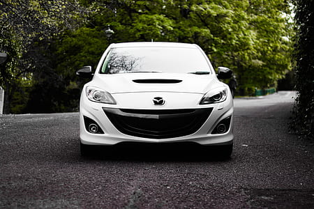 white Mazda on asphalt road between trees thumbnail