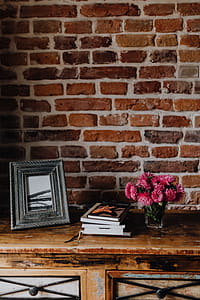 Photo frame, books and pink flowers in a vase on a wooden commode thumbnail