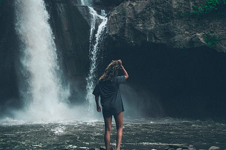 woman standing in front of waterfalls during daytime thumbnail