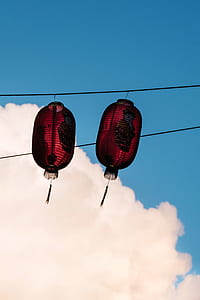 two red paper lanterns hanging on black string during daytime thumbnail