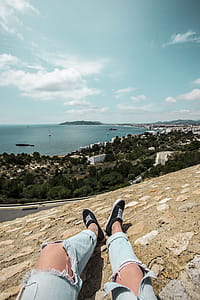 Man in Blue Tattered Jeans Sitting on Top of the Mountain thumbnail