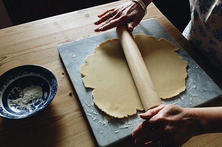 person holding roller pin while rolling dough thumbnail