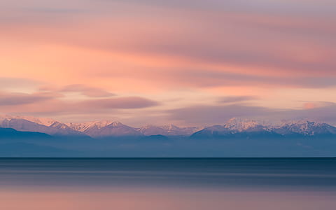 ocean near mountains under cloudy sky thumbnail