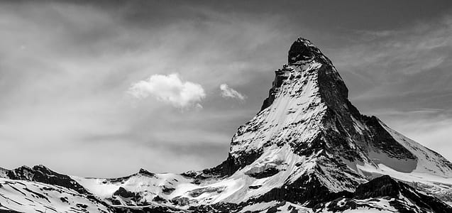 grayscale photography of snow capped mountain under cloudy sky thumbnail