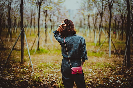 selective focus photo of woman standing in between of trees thumbnail
