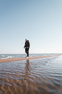 man walks between sea during daytime thumbnail