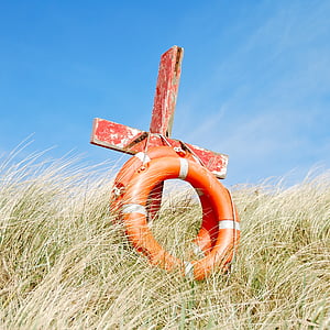 red wooden cross and two orange swim rings thumbnail